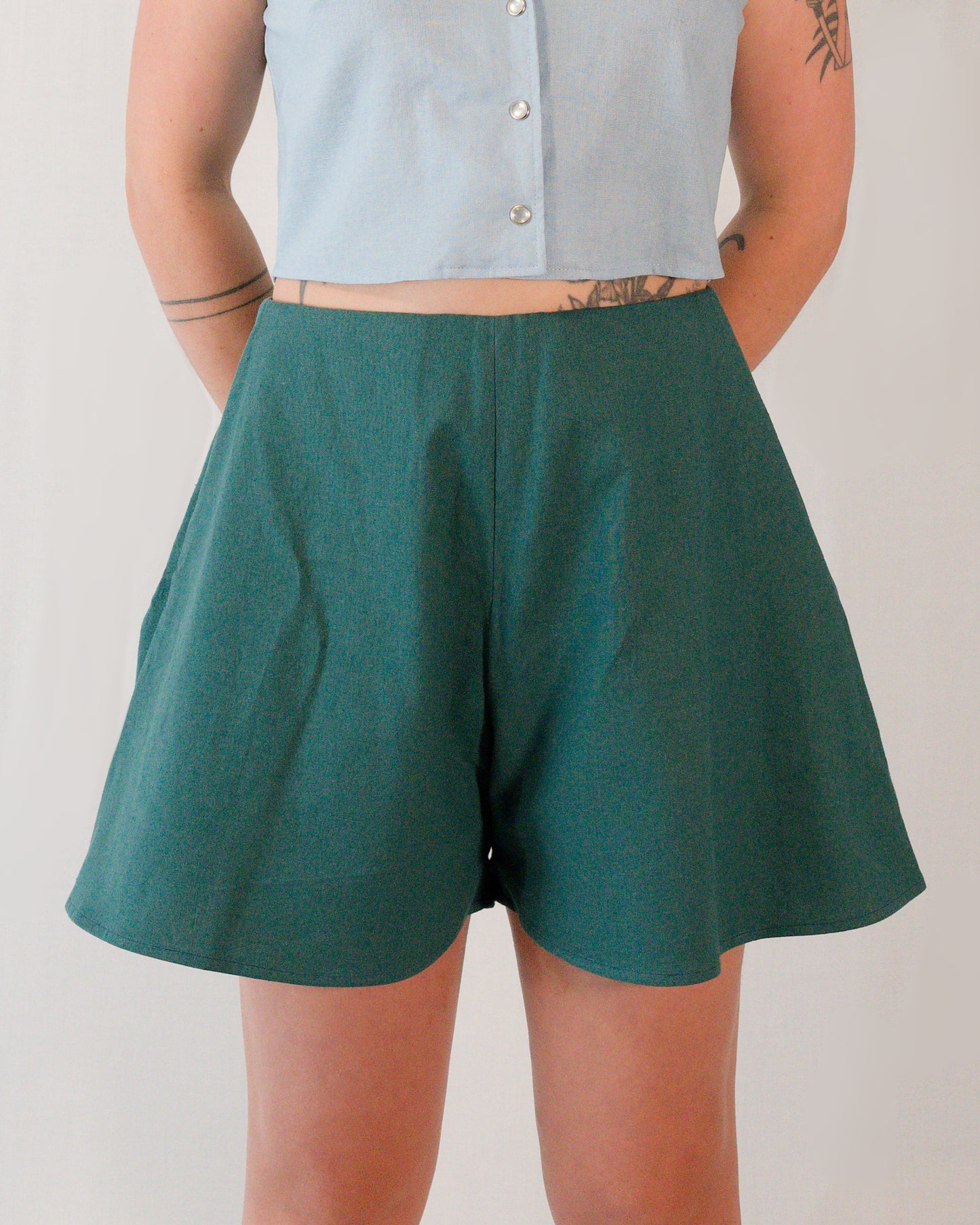 Front of flared shorts in deep emerald. Tidy front seam and no visible waistband.