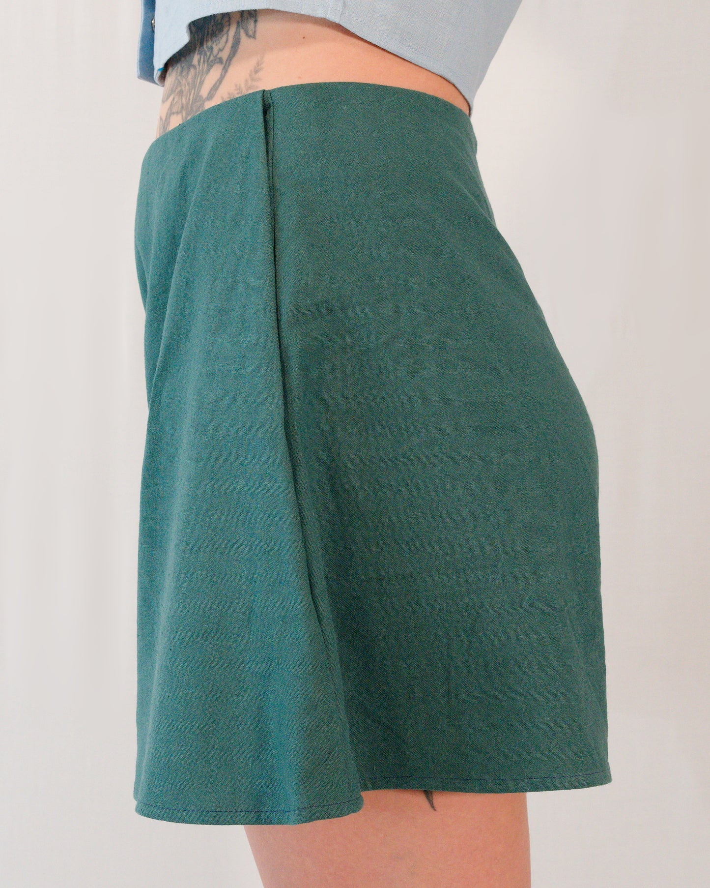 Left side of flared shorts in deep emerald. Side pocket is mostly hidden.