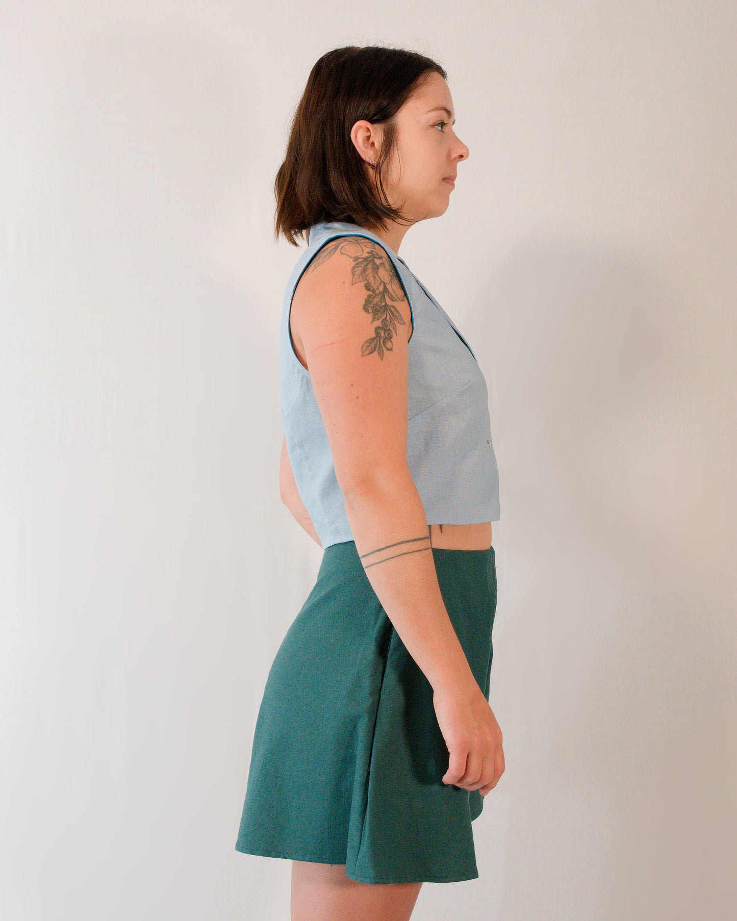 Right side of flared shorts in deep emerald, paired with a sleeveless blouse in skyline blue.