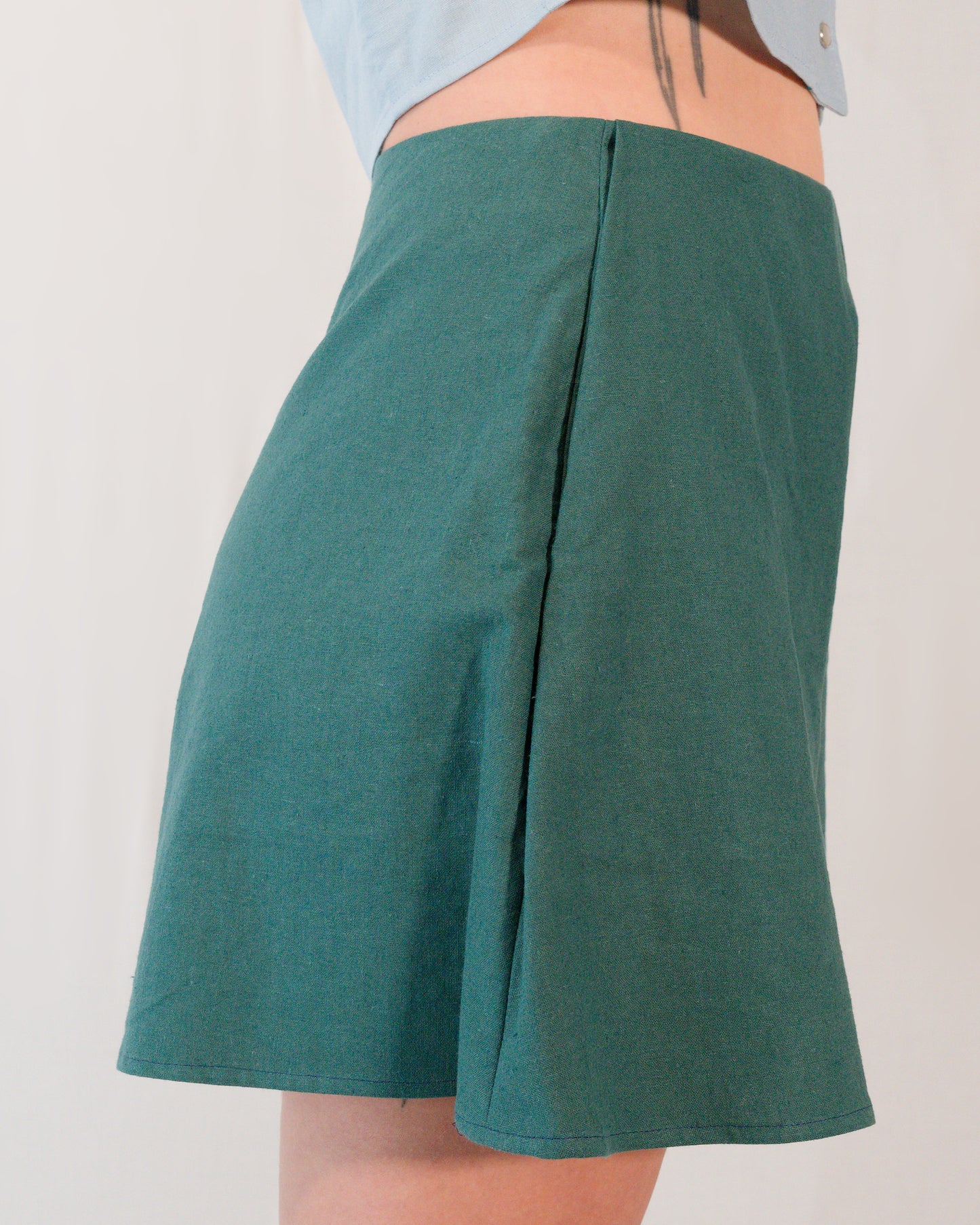 Right side of flared shorts in deep emerald. Side pocket is mostly hidden.