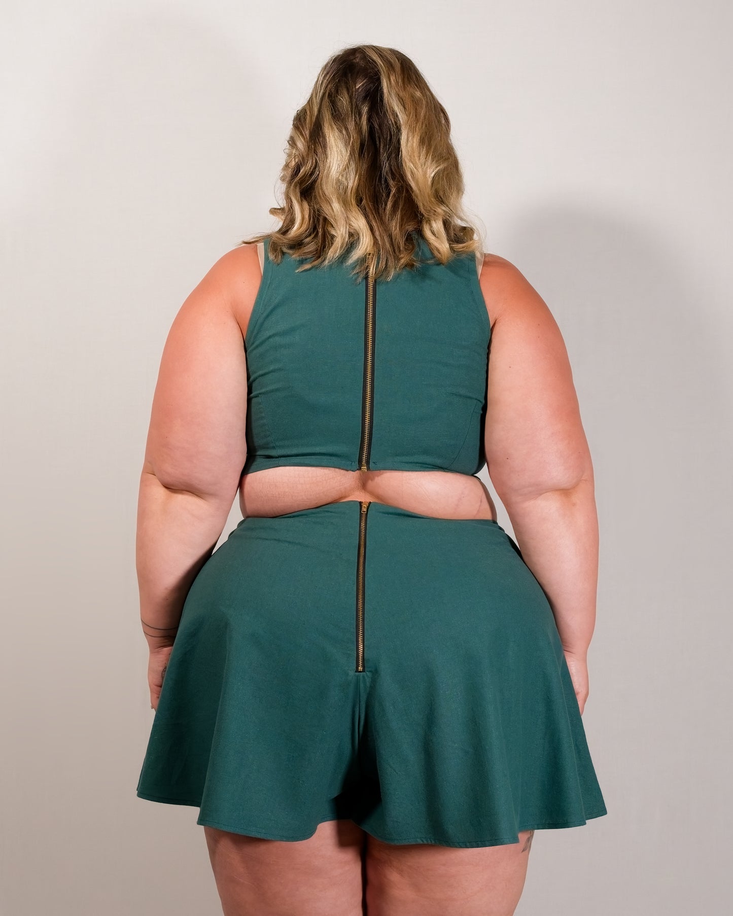 Back of flared shorts in deep emerald with a gold metal zipper closure centre-back. Zipper lines up with zipper on matching crop top.
