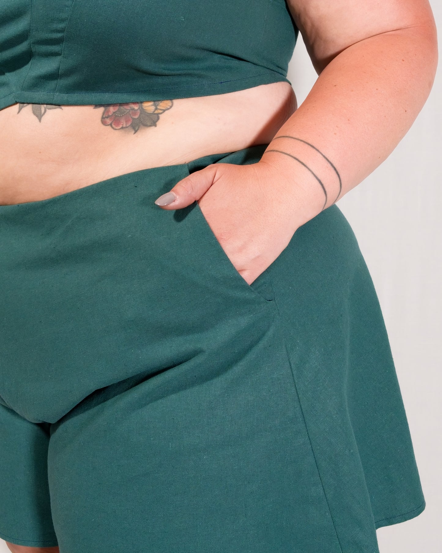 Close-up of hand in pocket on flared shorts in deep emerald.