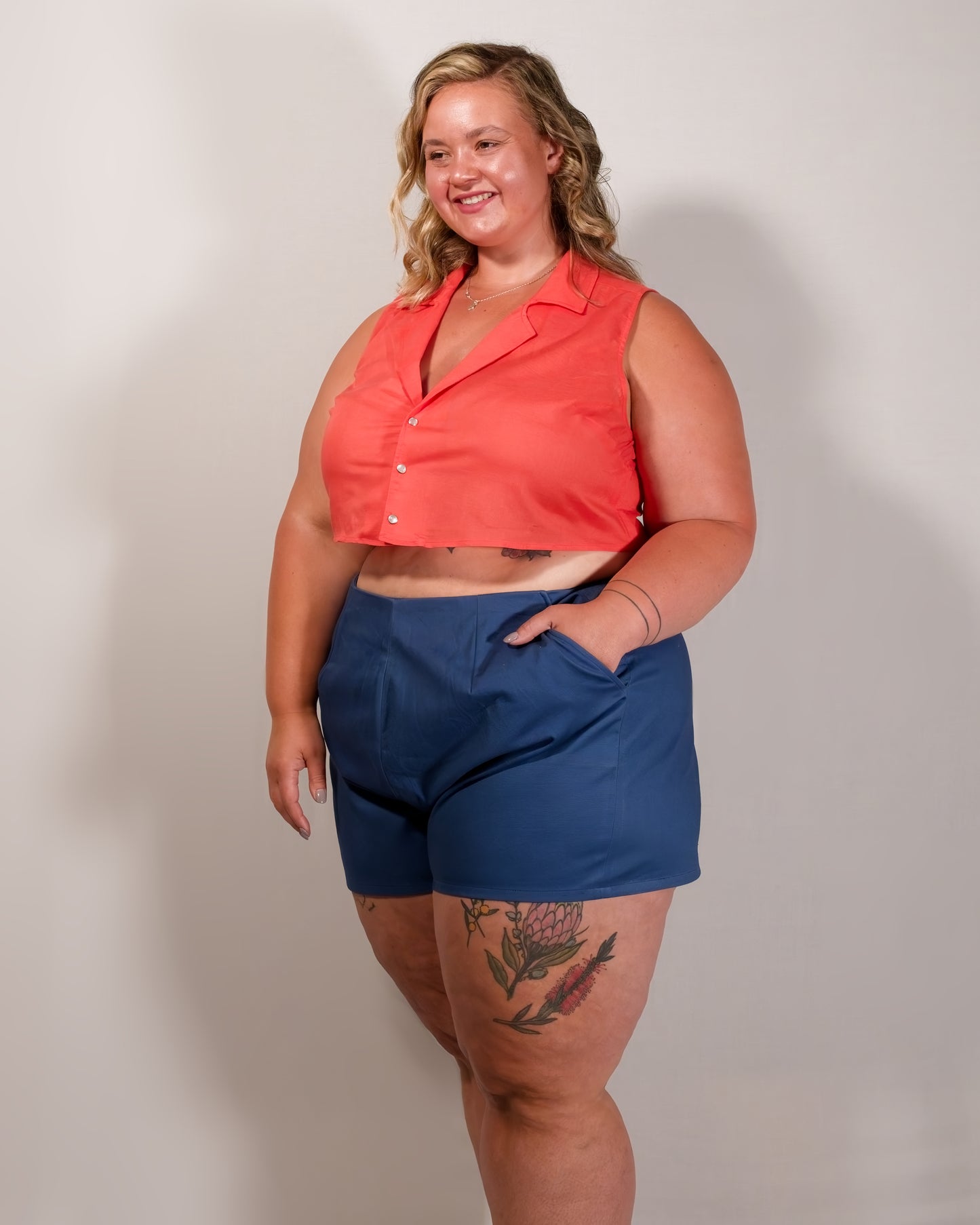Kingfisher A-line shorts in dark blue styled with a sleeveless blouse in callistemon red. Model has hand in pocket.
