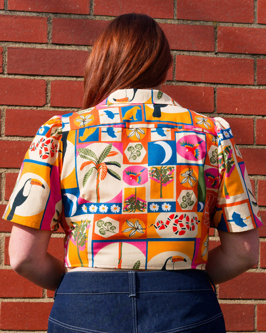 Person wearing a colorful patterned shirt against a brick wall