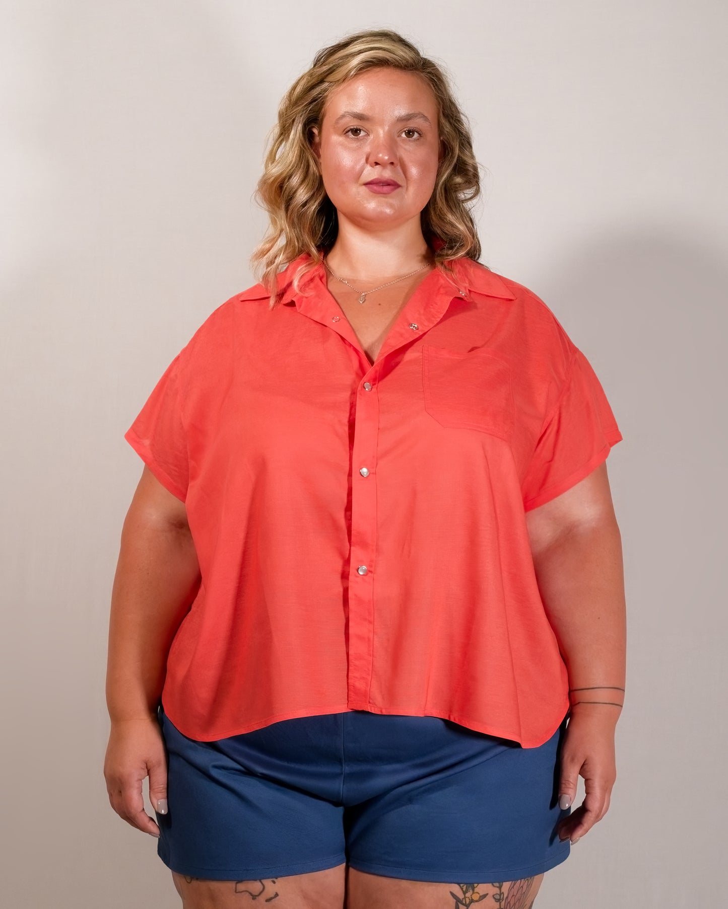 Front of a short-sleeved blouse in callistemon red with collar, pearl snaps and left breast pocket.