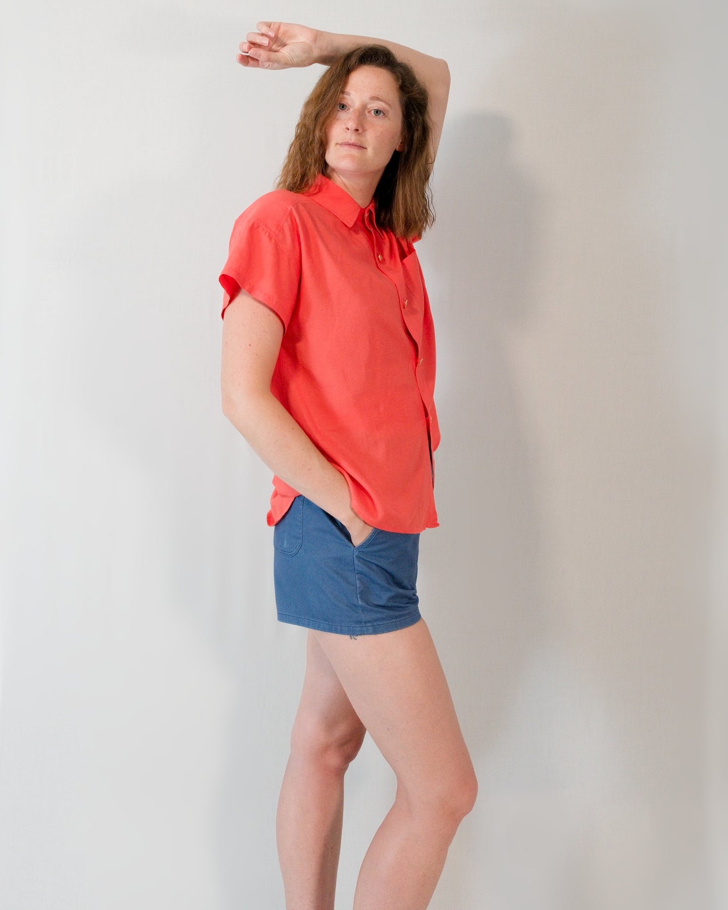 Short-sleeved button-down blouse in callistemon red styled with Kingfisher A-line shorts in blue.