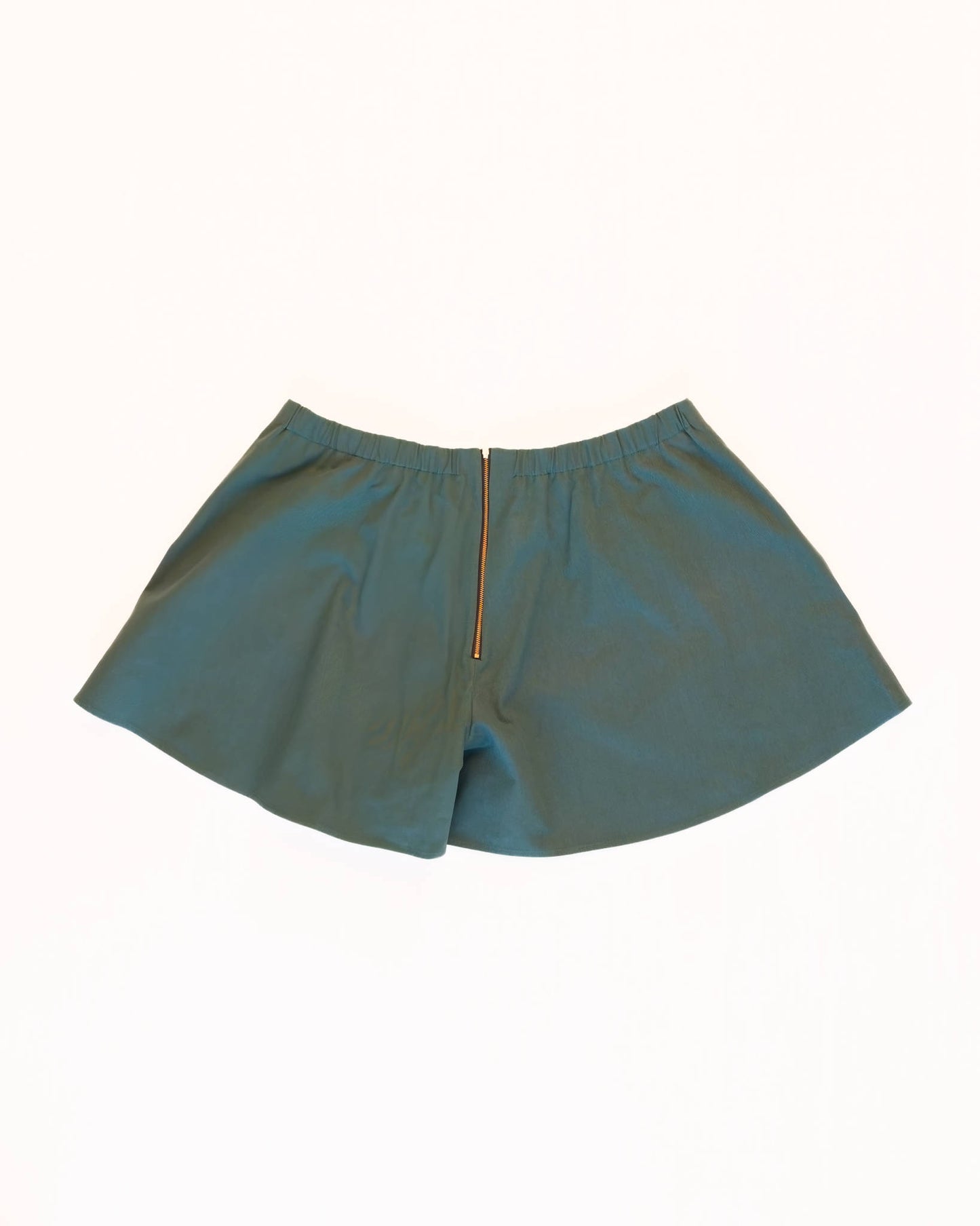 Back of teal skorts with a golden zipper and elastic waistband on a white background