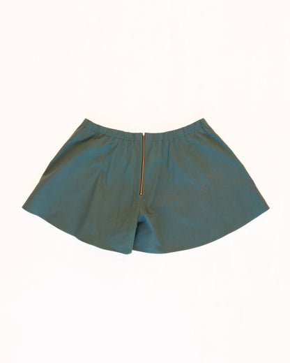 Back of teal skorts with a golden zipper and elastic waistband on a white background