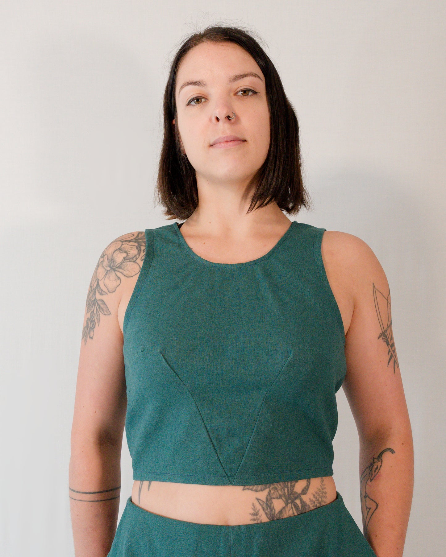 Front of a sleeveless crop top in deep emerald. The two waist darts form a V-shape below the bust.