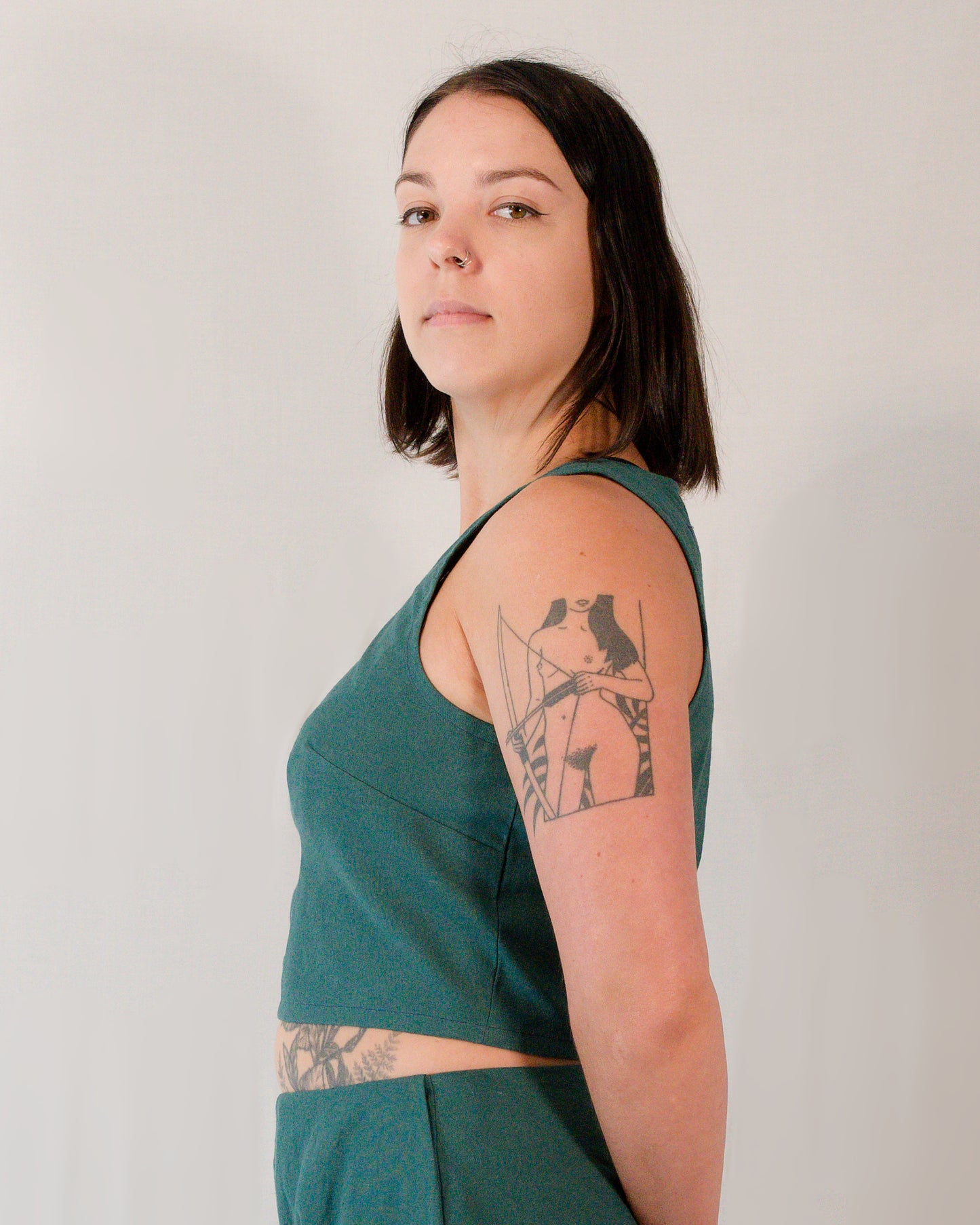 Left side of a sleeveless crop top in deep emerald.
