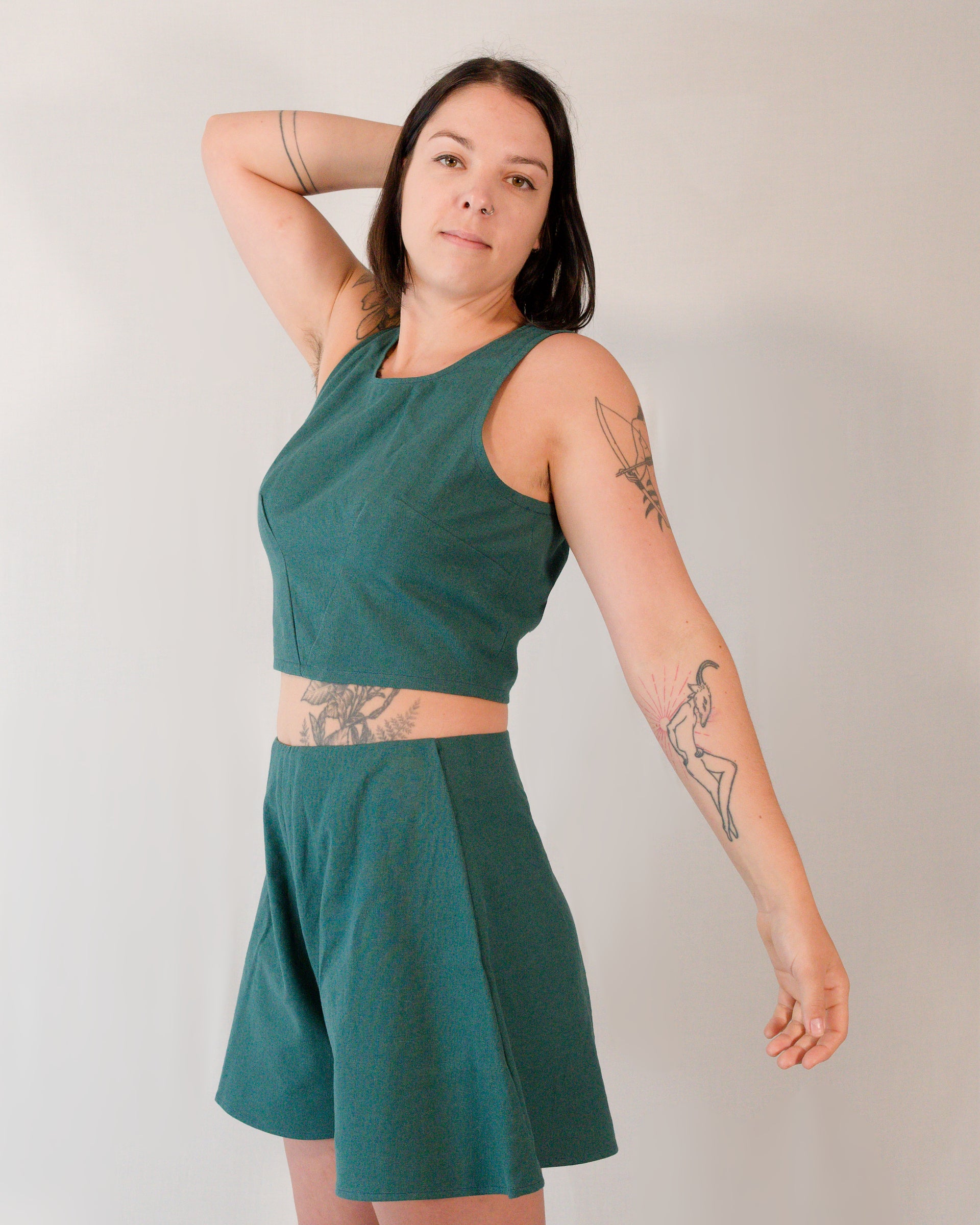 A sleeveless crop top paired with matching flared shorts, both in deep emerald.