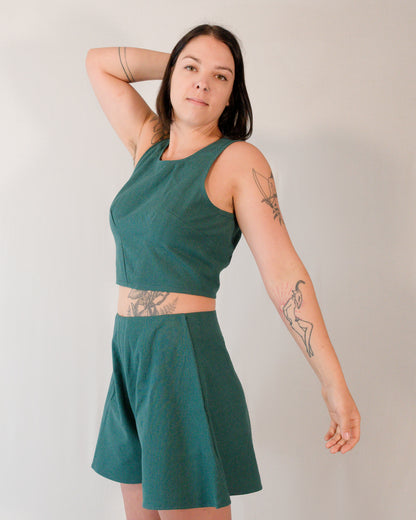 A sleeveless crop top paired with matching flared shorts, both in deep emerald.