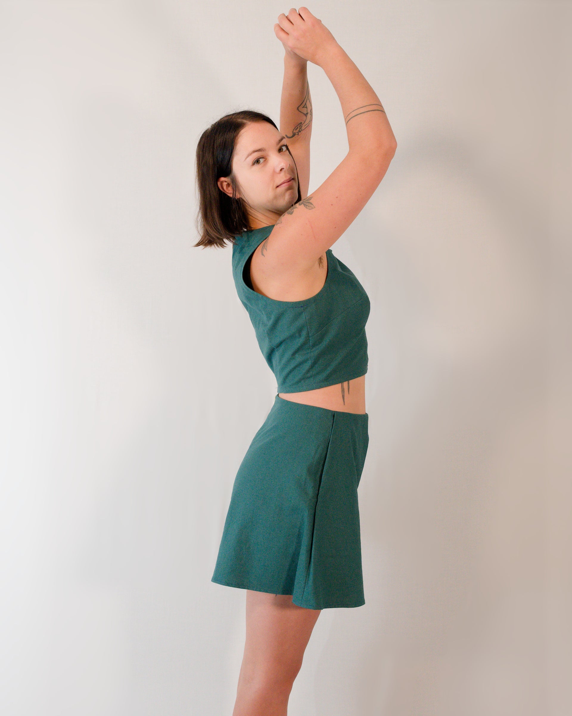 Right side of a sleeveless crop top paired with matching flared shorts, both in deep emerald.