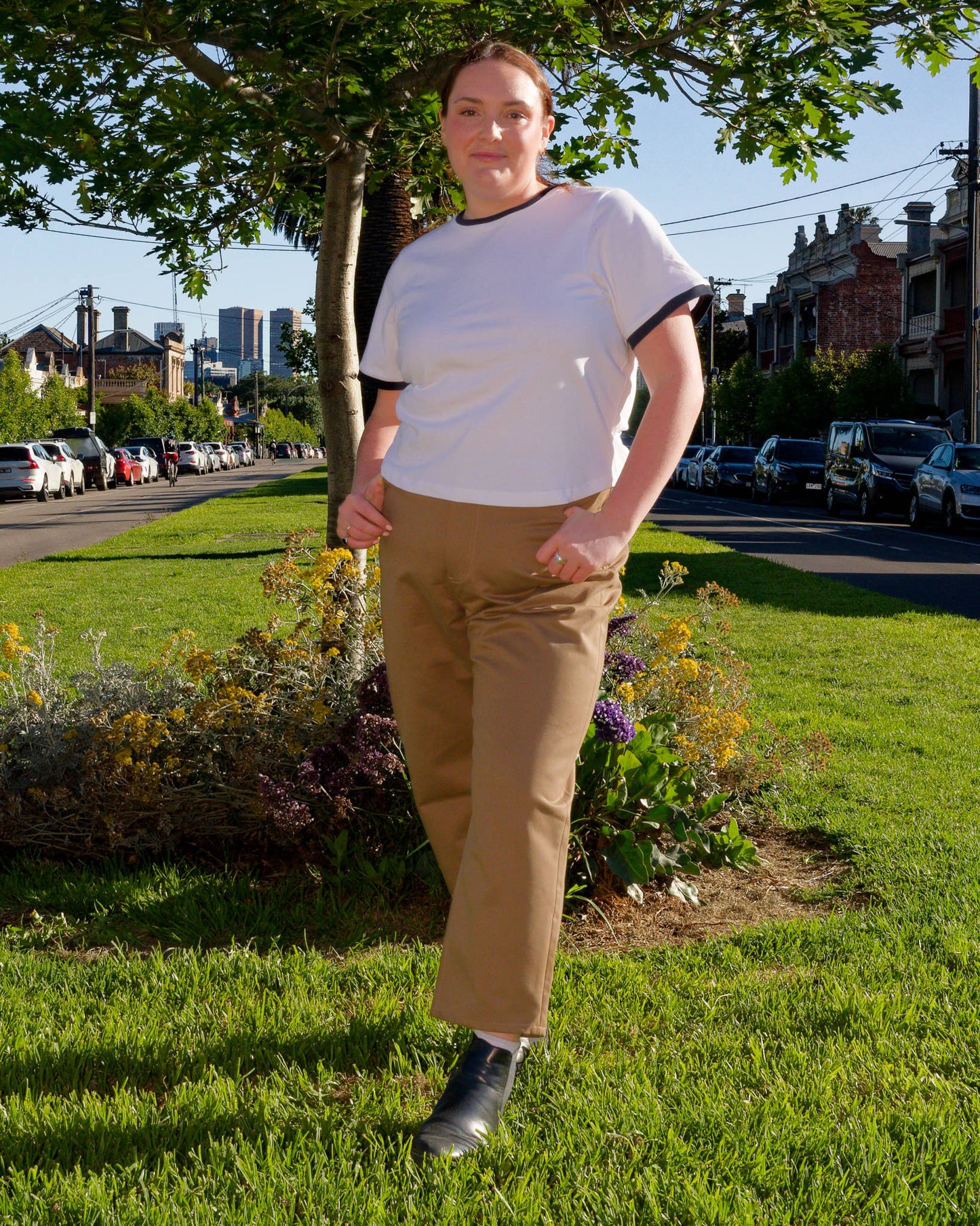 Lydia modelling a white t-shirt and khaki barrel-leg jeans on a nature strip.