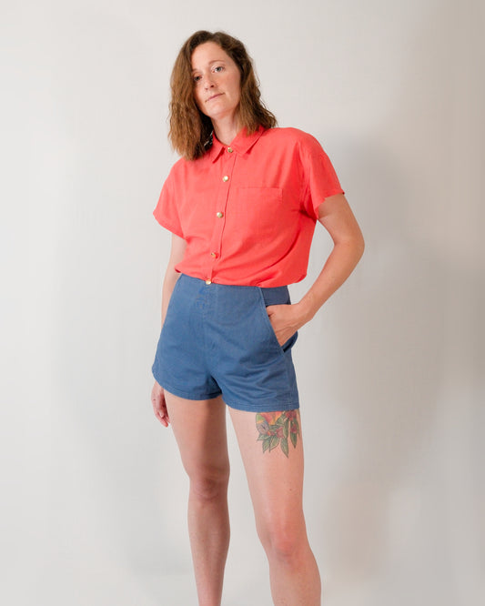 Kingfisher A-line shorts in dark blue paired with a short-sleeved blouse in callistemon red, tucked in.
