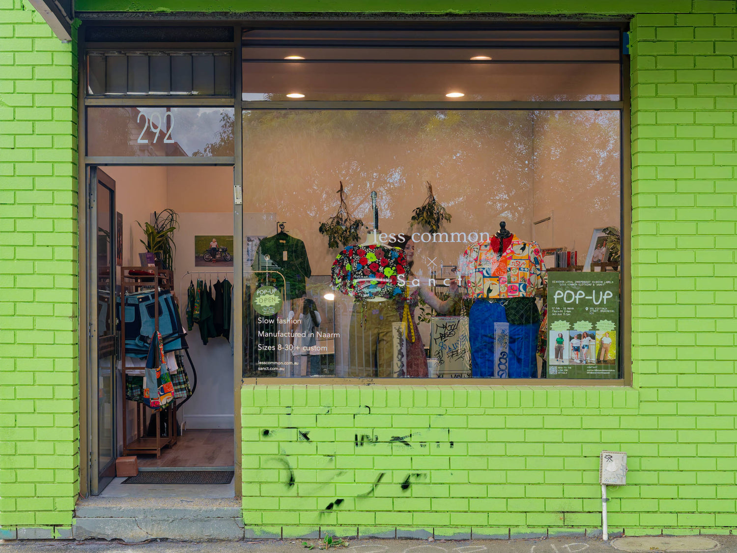 Green brick building with a store front displaying clothing items.