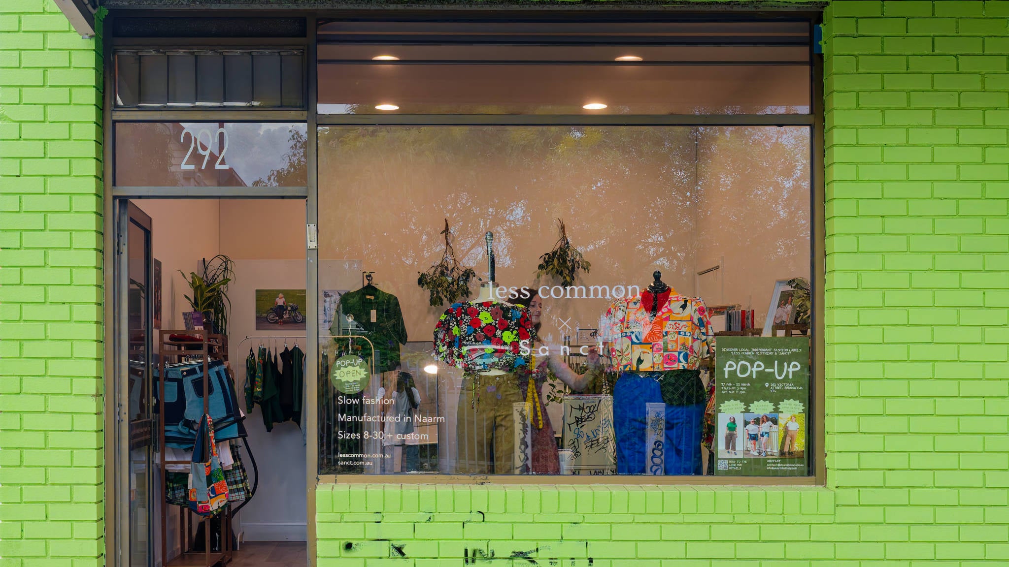 Storefront with a bright green brick wall and displaying colourful clothing items.