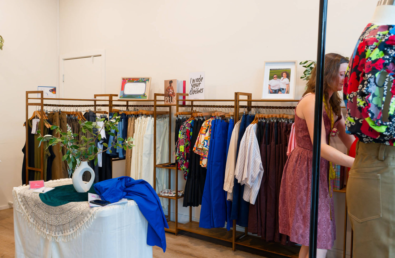 Clothing store interior with racks of clothing and a shop attendant