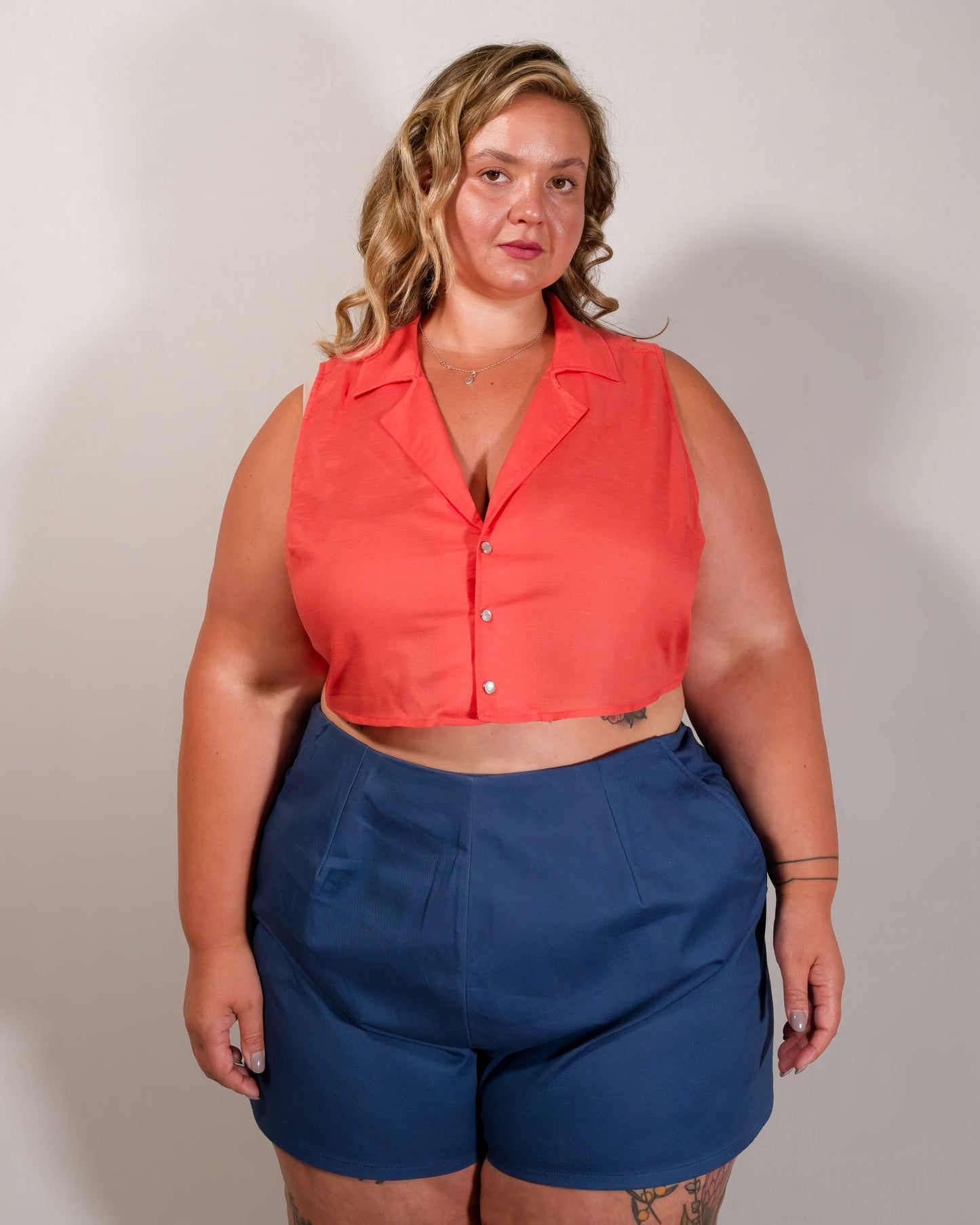 Sleeveless blouse in callistemon red with camp collar and pearl snaps. Paired with Kingfisher A-line shorts in blue.