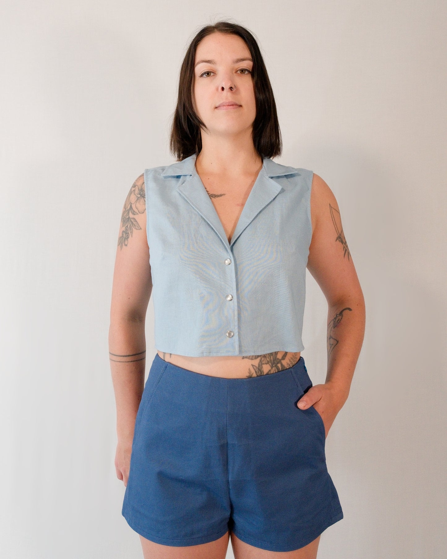 Front of sleeveless blouse in skyline blue with pearl snaps. Paired with Kingfisher A-line shorts in blue.
