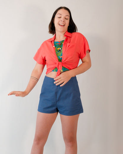 Short-sleeved blouse in callistemon red tied into a shirt knot. Paired with Kingfisher A-line shorts in blue.