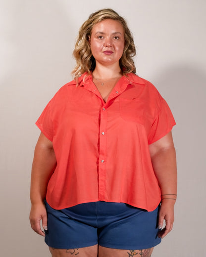 Front of a short-sleeved blouse in callistemon red with collar, pearl snaps and left breast pocket.