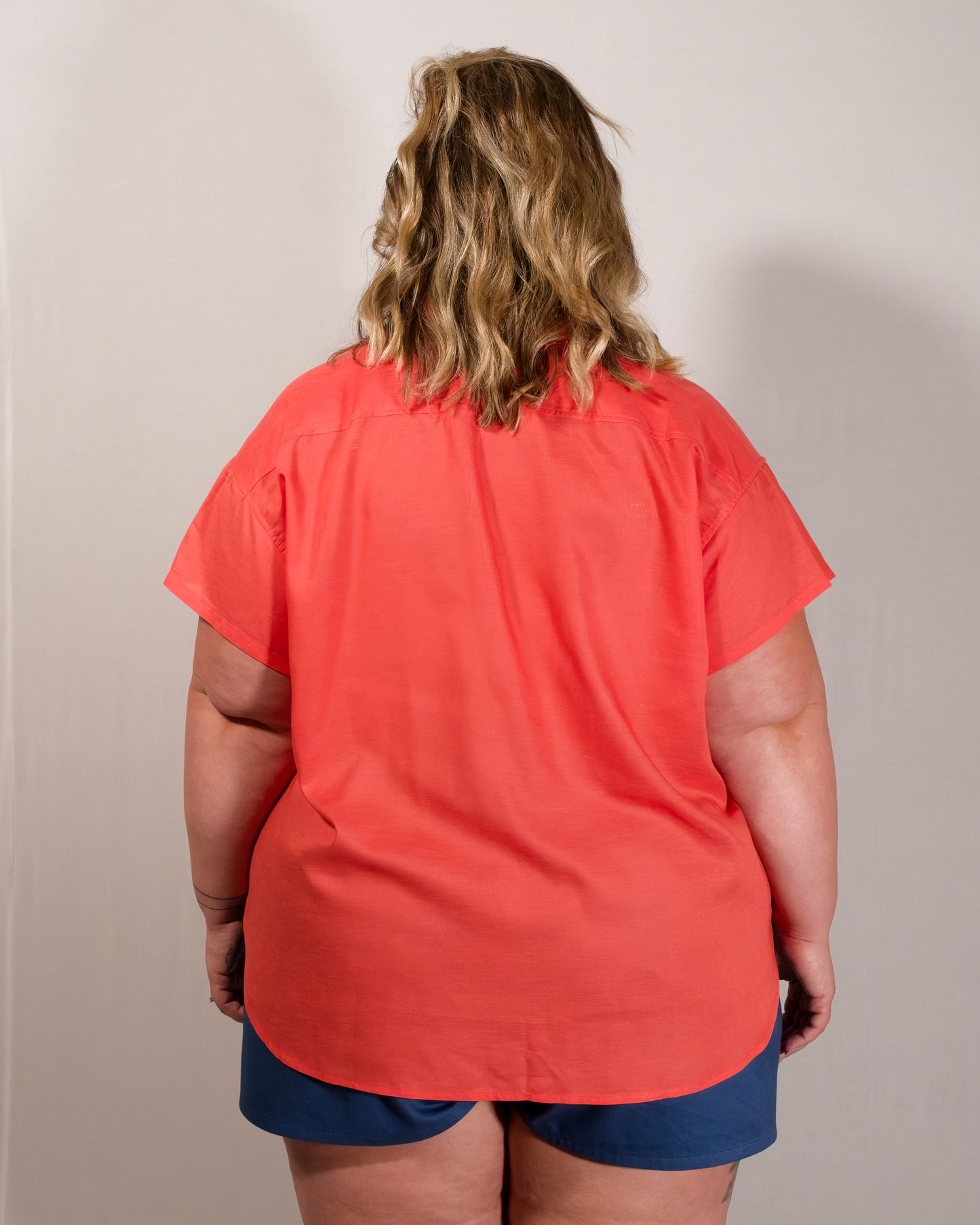 Back of a short-sleeved blouse in callistemon red. Length is in line with buttocks.