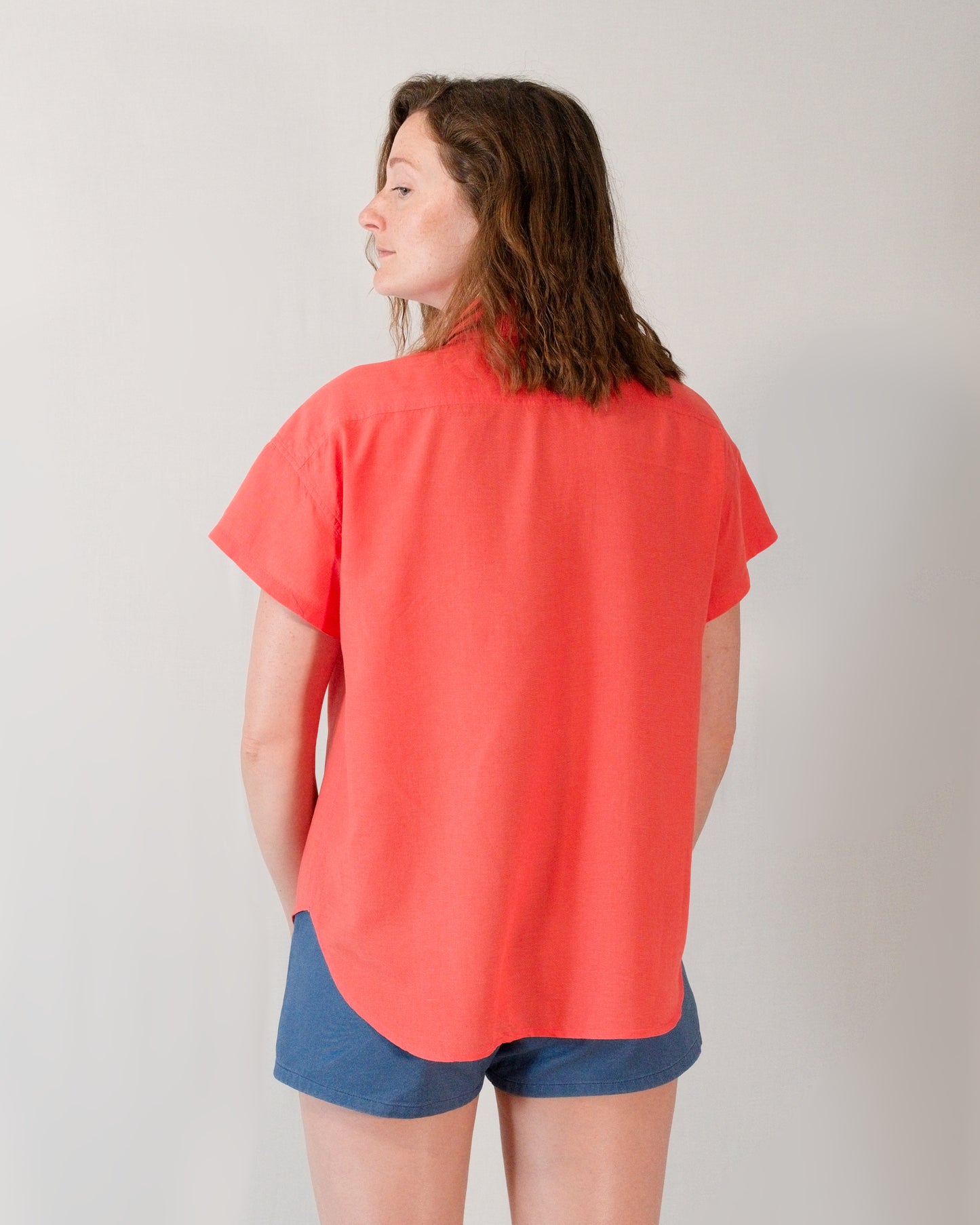 Back of a short-sleeved blouse in callistemon red. Length is in line with buttocks.