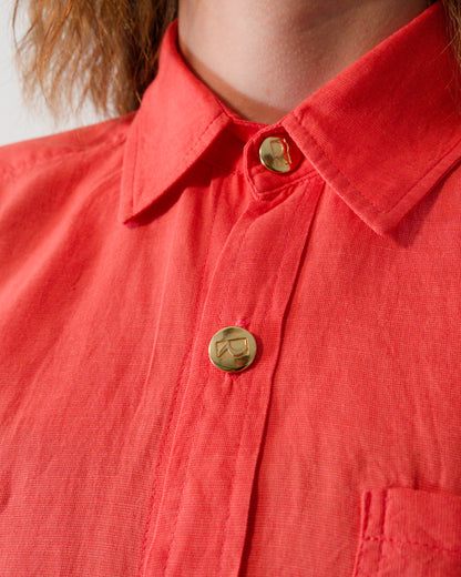 Close-up of collar and brass buttons on short-sleeved blouse in callistemon red.