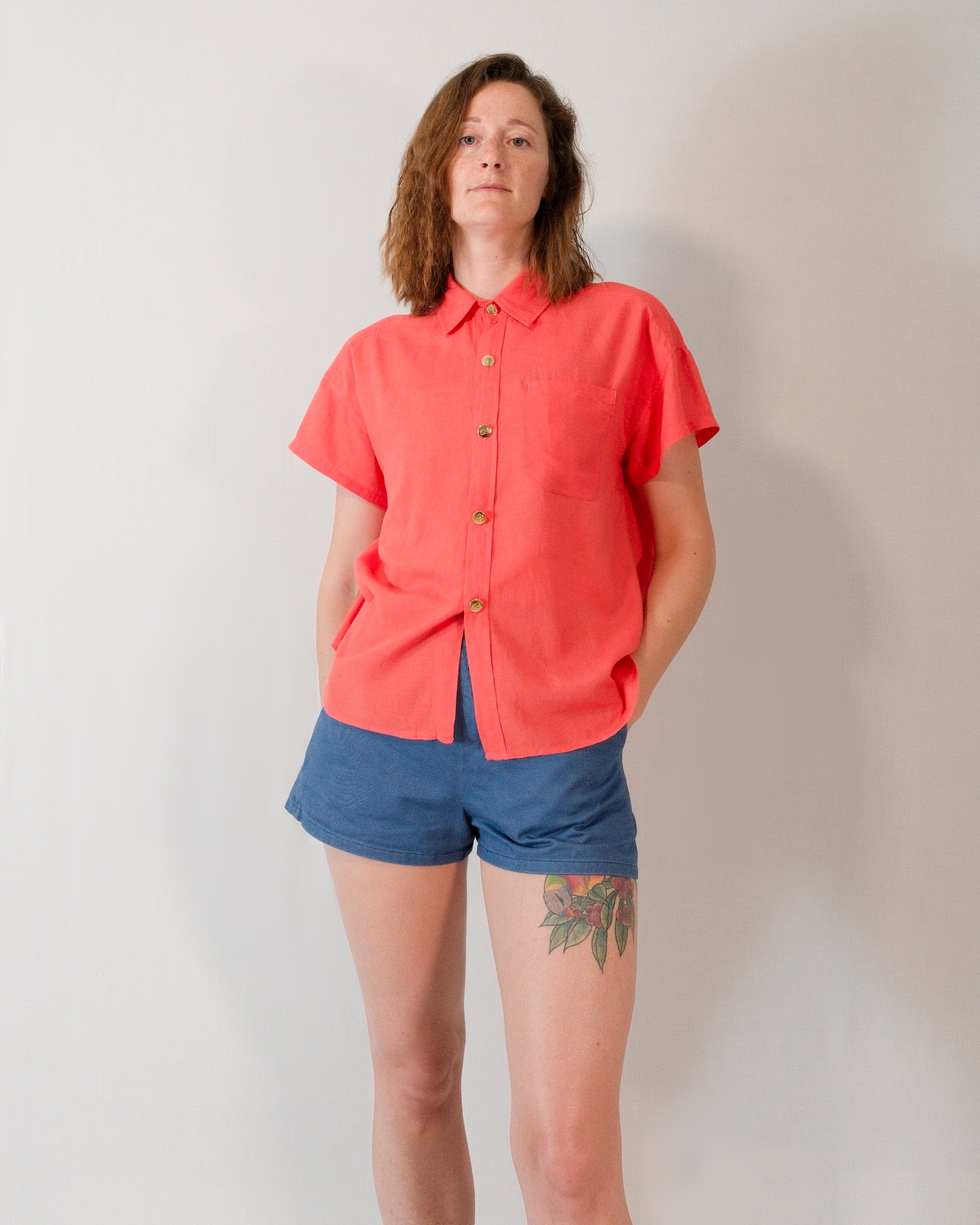 Front of a short-sleeved blouse in callistemon red styled with Kingfisher A-line shorts in blue.